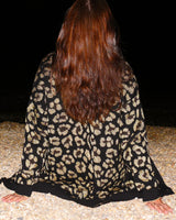 cardigan en jacquard leopard fond noir taches dores vue de dos a la plage-allrich